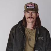 John Morgan wearing a green tshirt, black jacket, and green cap